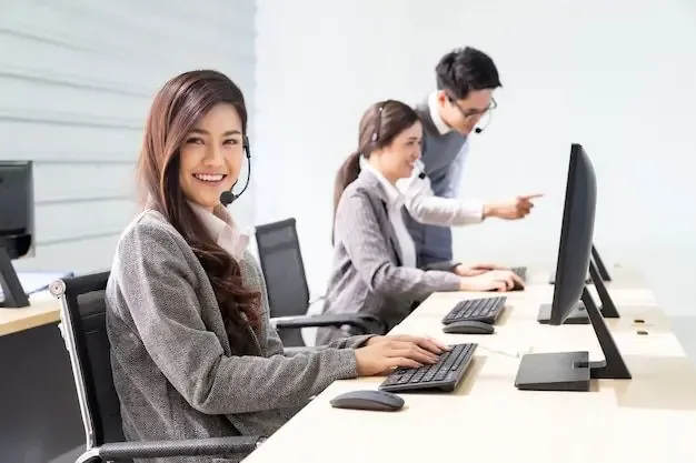 Smiling female agent wearing headset at a lead generation call center, working alongside teammates to handle customer inquiries on desktop computers.
