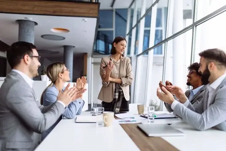 Female executive presenting lead generation call center performance insights to a group of business professionals in a modern office.
