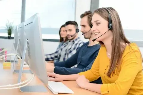 Multilingual technical support outsourcing team providing remote customer service using headsets and desktop computers.