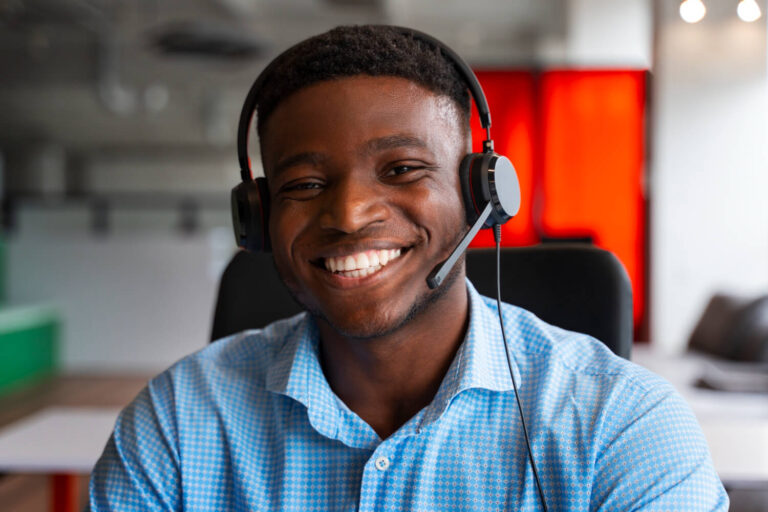 A male customer rep from an EMEA call center based in North Africa smiles for the camera as he provides pre-sales/after-sales customer service support solutions to native-speaking customers that are interested in a go-global e-commerce store's fashion products.